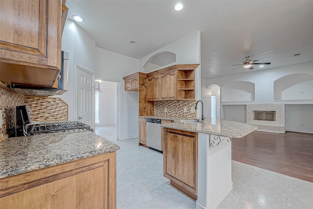 kitchen featuring sink, light tile patterned floors, stainless steel dishwasher, light stone countertops, and backsplash