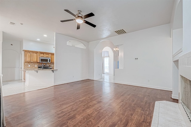 unfurnished living room featuring a fireplace, ceiling fan, and light hardwood / wood-style floors