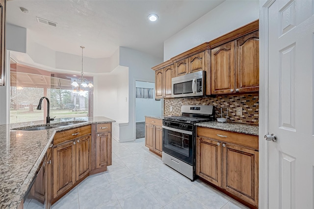 kitchen featuring light tile patterned flooring, sink, pendant lighting, stainless steel appliances, and light stone countertops