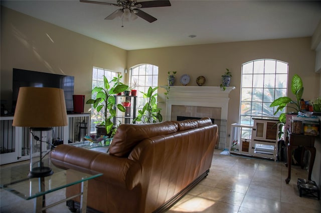 living room with a tiled fireplace and ceiling fan