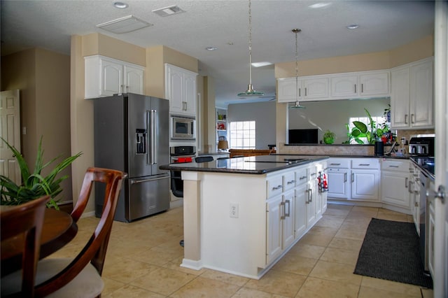 kitchen with a center island, hanging light fixtures, light tile patterned floors, appliances with stainless steel finishes, and white cabinets