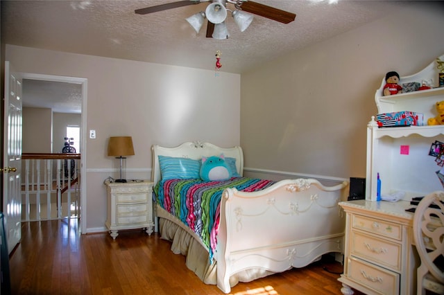 bedroom with a textured ceiling, ceiling fan, and hardwood / wood-style flooring