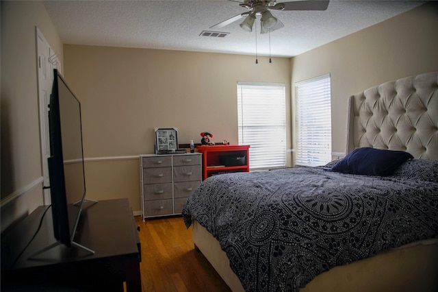 bedroom with hardwood / wood-style flooring, a textured ceiling, and ceiling fan