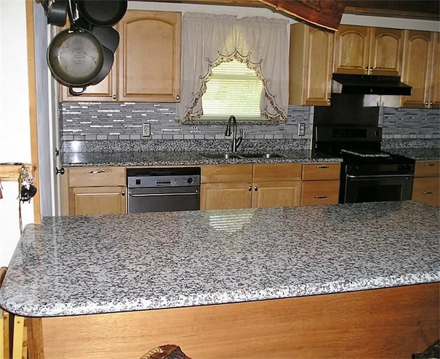 kitchen with black range oven, light stone countertops, sink, and decorative backsplash