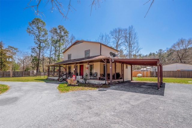 view of front of house featuring a porch, a front yard, fence, and an attached carport