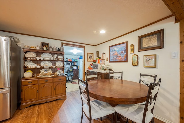 dining room featuring light wood finished floors and crown molding