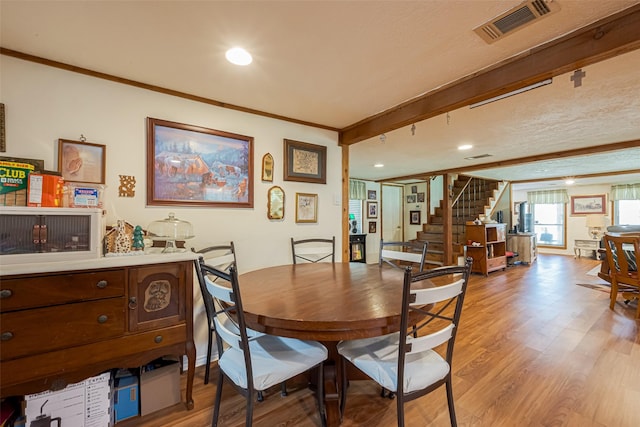 dining space with stairway, light wood-style flooring, visible vents, and crown molding