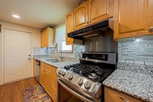 kitchen featuring a sink, light stone counters, stainless steel range with gas cooktop, and under cabinet range hood