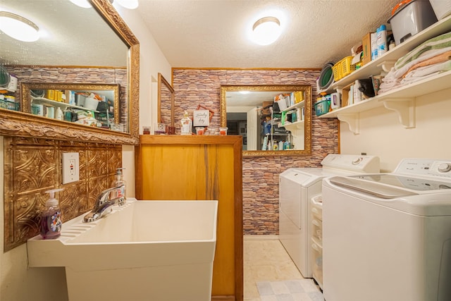 clothes washing area featuring laundry area, a sink, a textured ceiling, and separate washer and dryer