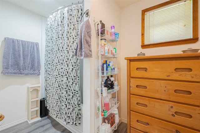 full bathroom featuring curtained shower, baseboards, and wood finished floors