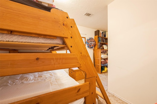 bedroom featuring visible vents, light carpet, and a textured ceiling