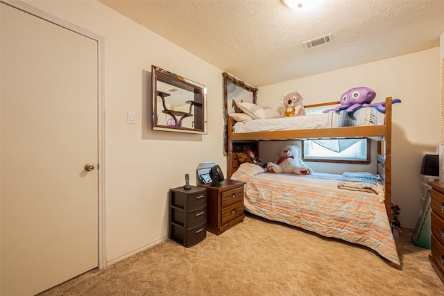 bedroom featuring light carpet, a textured ceiling, and visible vents