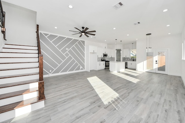 unfurnished living room featuring sink, light hardwood / wood-style floors, and ceiling fan