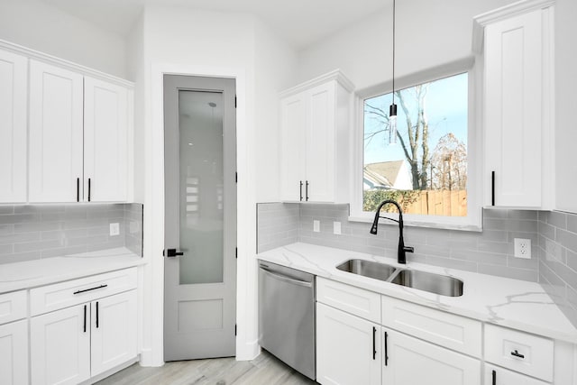 kitchen featuring sink, dishwasher, white cabinets, pendant lighting, and backsplash