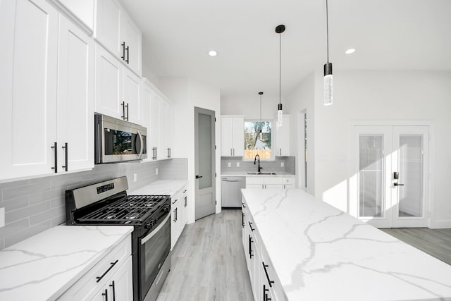 kitchen featuring light stone counters, stainless steel appliances, decorative light fixtures, and white cabinets