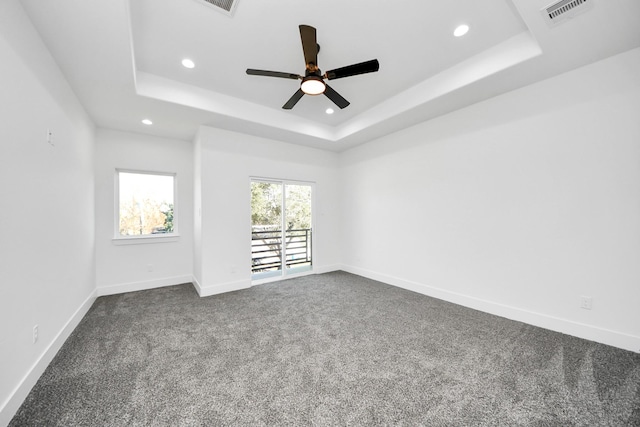 carpeted spare room featuring a tray ceiling and ceiling fan