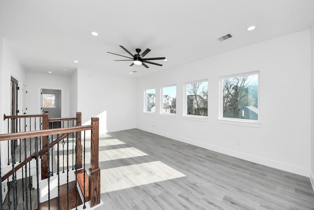 empty room featuring ceiling fan, plenty of natural light, and light wood-type flooring