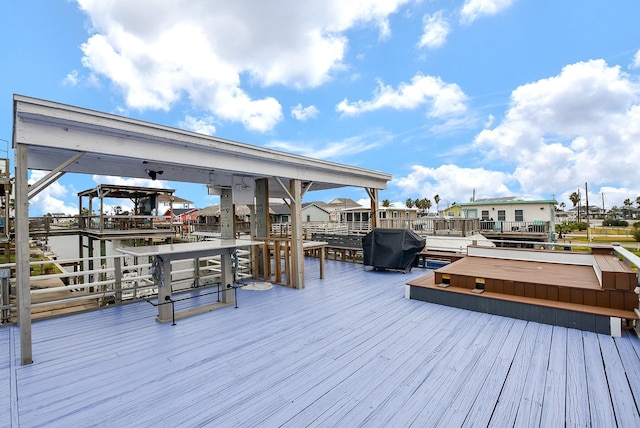 wooden deck featuring area for grilling, a jacuzzi, and a water view