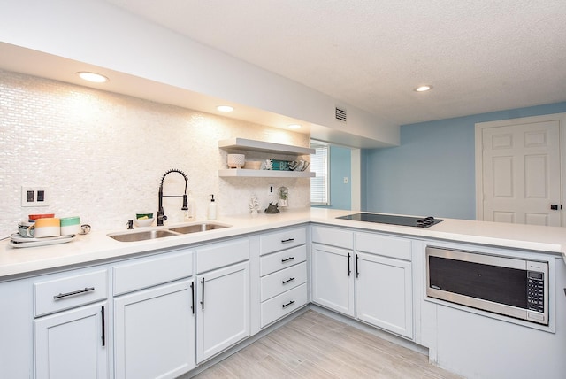 kitchen featuring white cabinetry, sink, backsplash, and light wood-type flooring