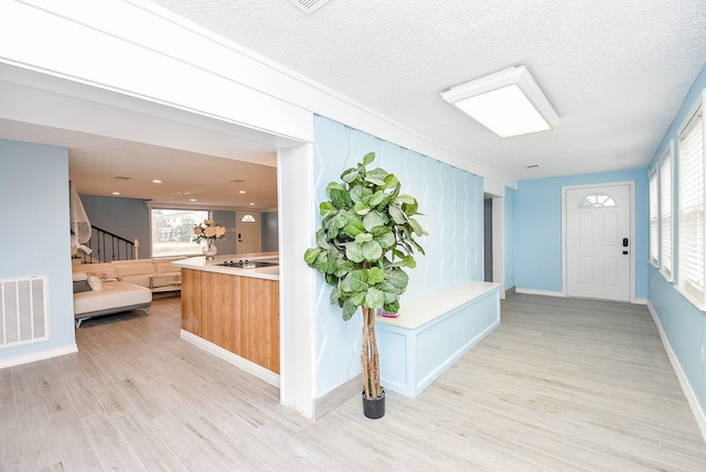 hallway featuring light hardwood / wood-style floors and a textured ceiling