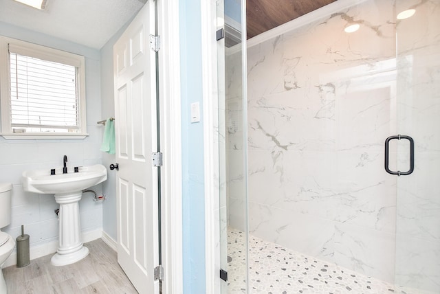 bathroom featuring wood-type flooring, a shower with door, and toilet