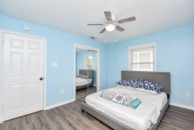 bedroom with dark wood-type flooring, ceiling fan, a closet, and a textured ceiling