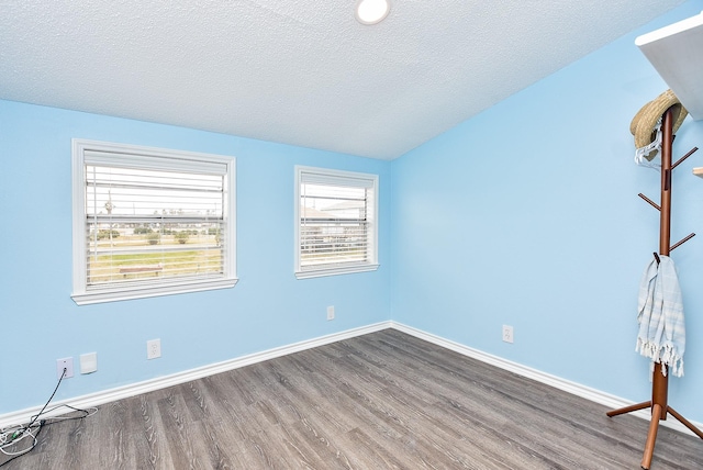 empty room with wood-type flooring and a textured ceiling