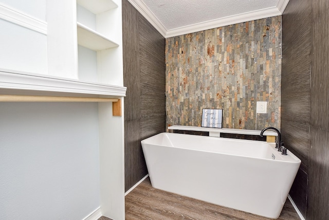 bathroom with hardwood / wood-style flooring, crown molding, a textured ceiling, and a tub