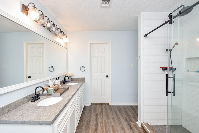 bathroom with hardwood / wood-style flooring, vanity, an enclosed shower, and a textured ceiling