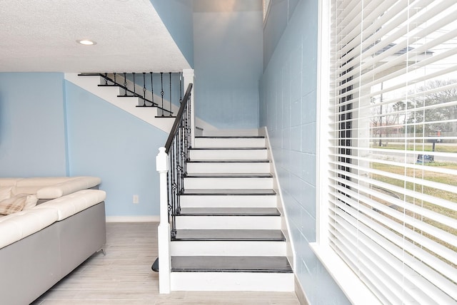 stairway featuring wood-type flooring and a textured ceiling