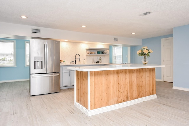 kitchen with white cabinetry, light hardwood / wood-style floors, stainless steel fridge with ice dispenser, and a kitchen island