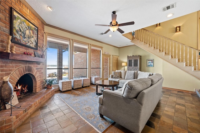 living room with ornamental molding, a textured ceiling, ceiling fan, and a fireplace