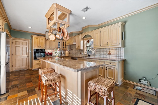 kitchen featuring sink, a breakfast bar area, black appliances, a center island, and backsplash