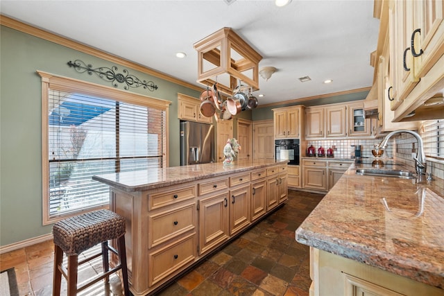 kitchen with sink, a center island, oven, stainless steel fridge, and light stone countertops