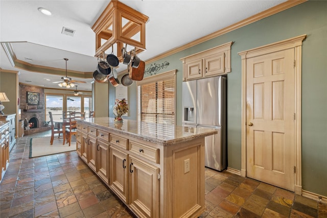 kitchen featuring stainless steel fridge with ice dispenser, crown molding, a center island, and a brick fireplace