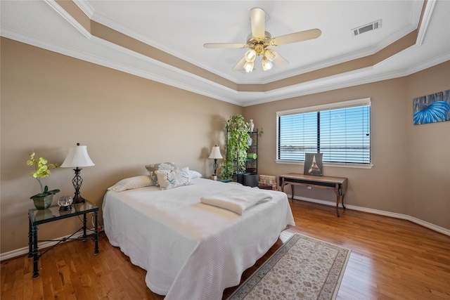 bedroom with a tray ceiling, wood-type flooring, and ceiling fan