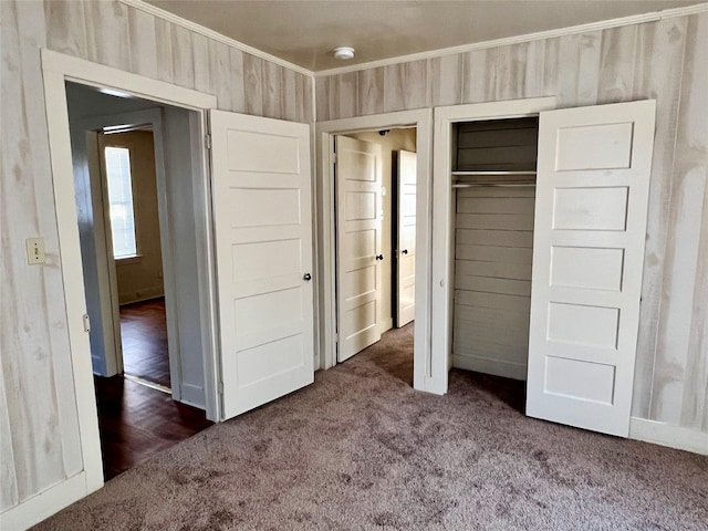 unfurnished bedroom featuring crown molding, dark carpet, and a closet