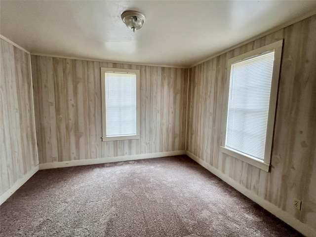 carpeted spare room featuring wood walls