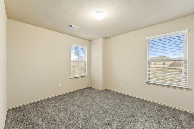 empty room with a textured ceiling and dark carpet