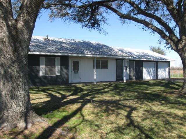 back of property featuring a garage and a yard