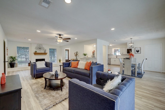 living room featuring ceiling fan, plenty of natural light, and light wood-type flooring