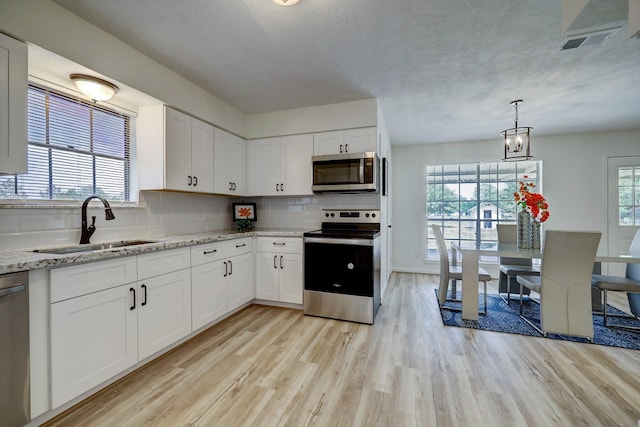 kitchen featuring decorative backsplash, light hardwood / wood-style floors, white cabinets, and appliances with stainless steel finishes