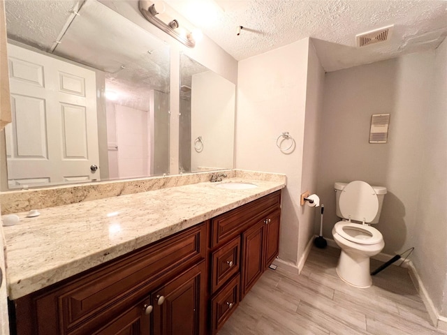 bathroom featuring hardwood / wood-style flooring, vanity, toilet, and a textured ceiling