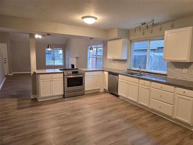 kitchen with sink, white cabinetry, hanging light fixtures, stainless steel appliances, and tasteful backsplash