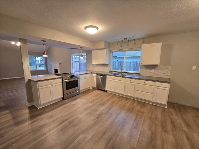 kitchen featuring hanging light fixtures, white cabinetry, appliances with stainless steel finishes, and sink