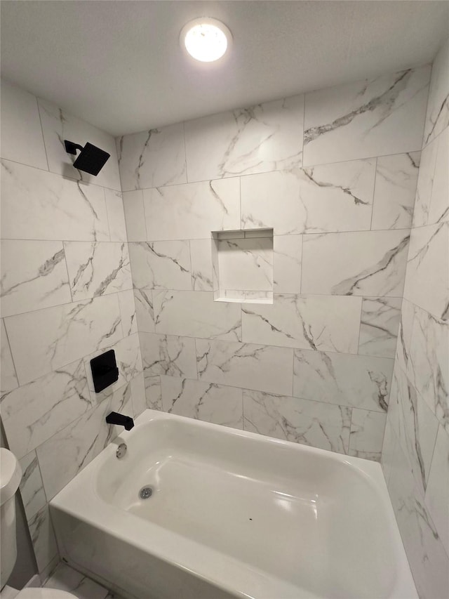 bathroom featuring tiled shower / bath combo and toilet