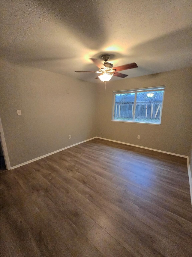 unfurnished room with ceiling fan, dark wood-type flooring, and a textured ceiling