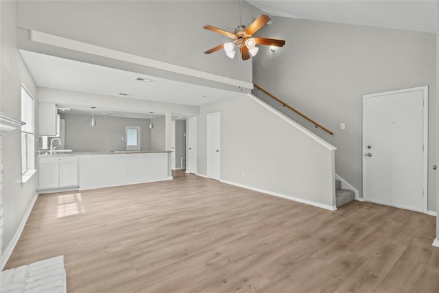 22706 Braken Carter Ln, Katy, TX 77449 - unfurnished living room with a ceiling fan, light wood-style floors, stairs, and high vaulted ceiling