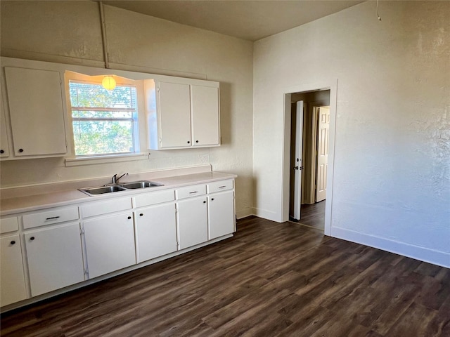 kitchen featuring sink, dark wood-type flooring, white cabinets, and decorative light fixtures