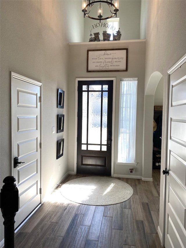 foyer entrance featuring dark wood-type flooring, a high ceiling, and a notable chandelier